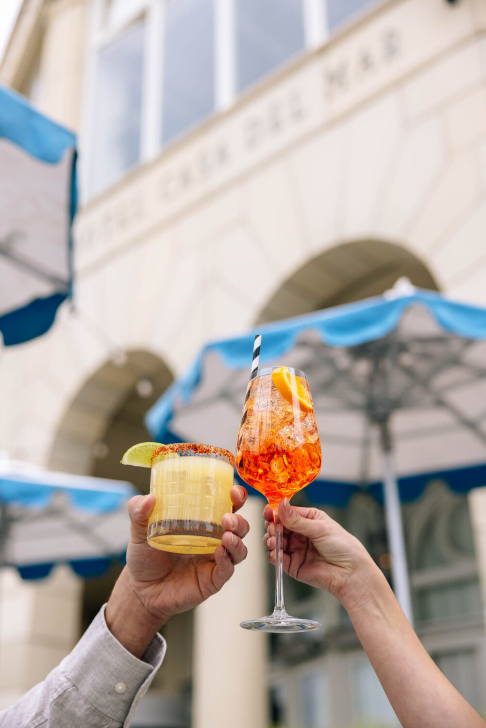 people clinking two cocktails in the air for a celebratory cheers