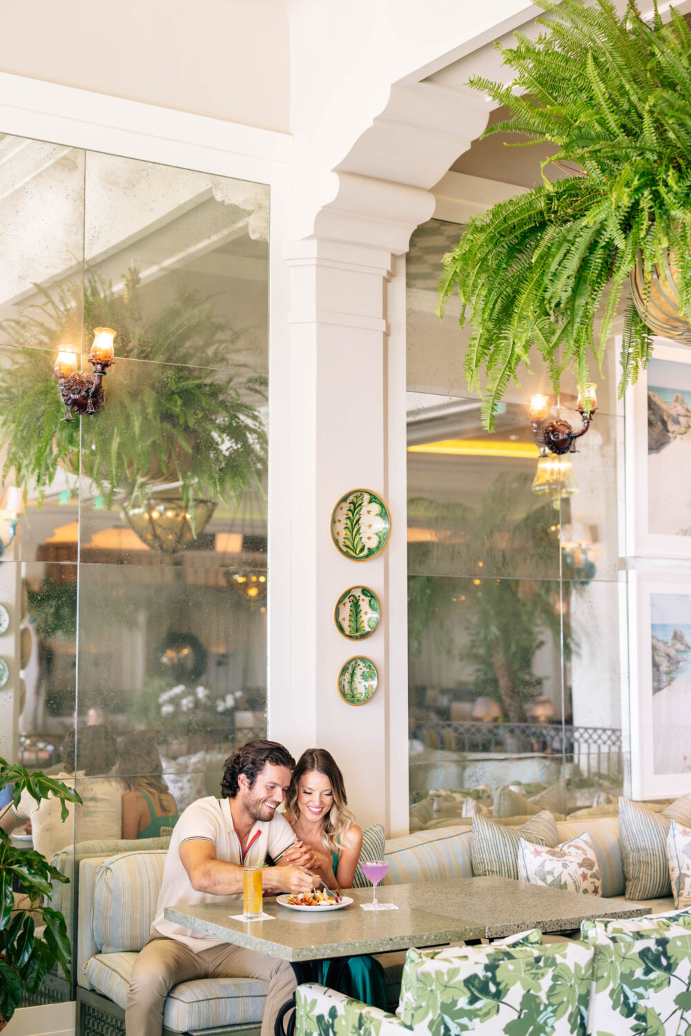 couple sitting side by side at a table with cocktails and appetizers