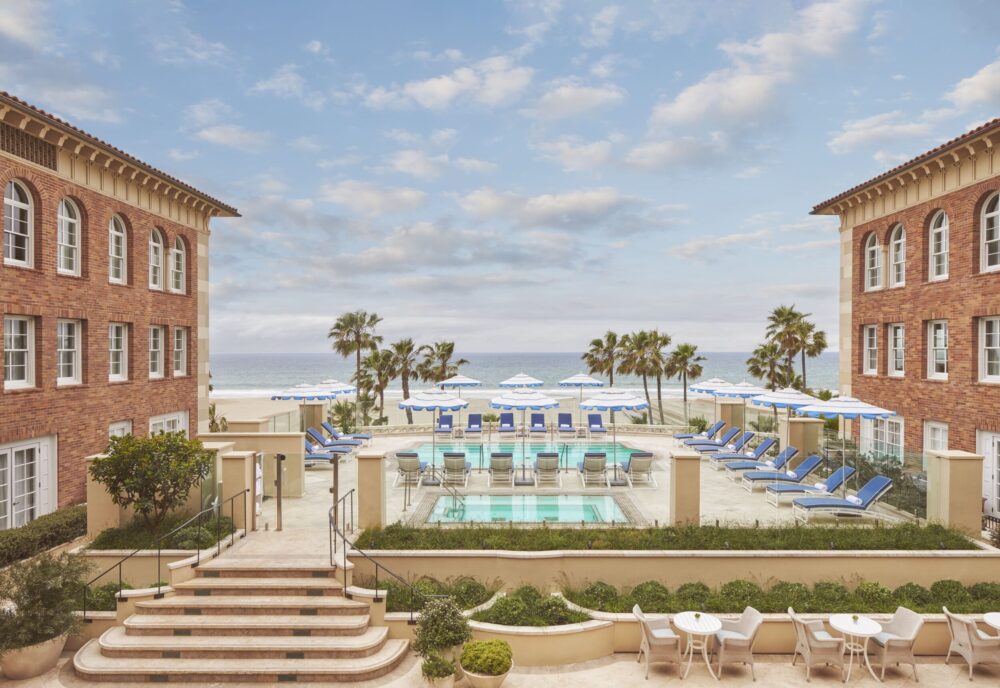 The pool at Hotel Casa del Mar features blue and white umbrellas, offering stunning ocean views.