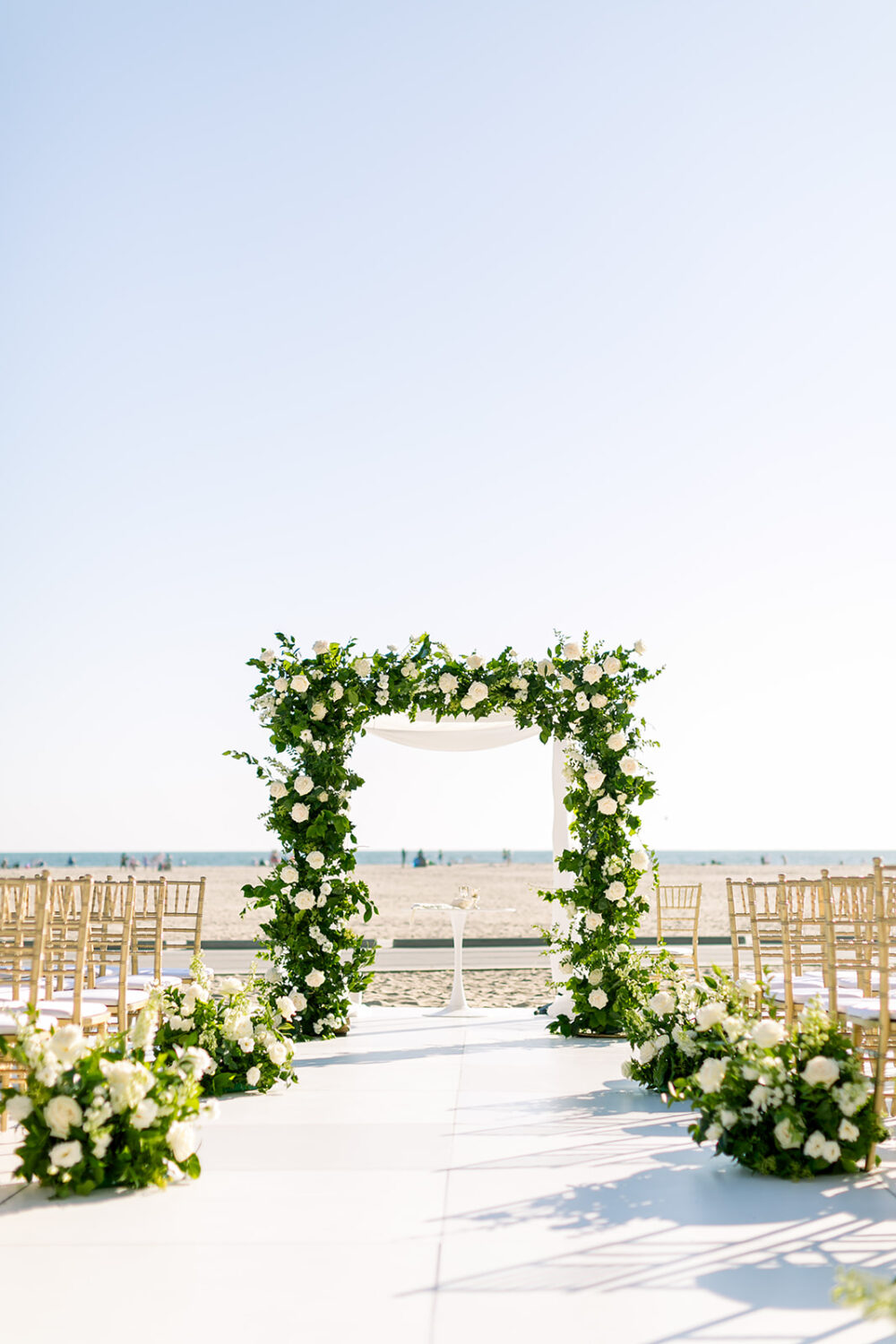 Wedding venue at Hotel Casa Del Mar with a floral arch decorated with white roses & gold chairs.