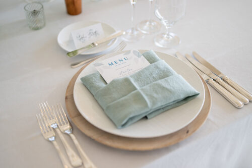 place setting with a teal napkin and custom menu placed inside