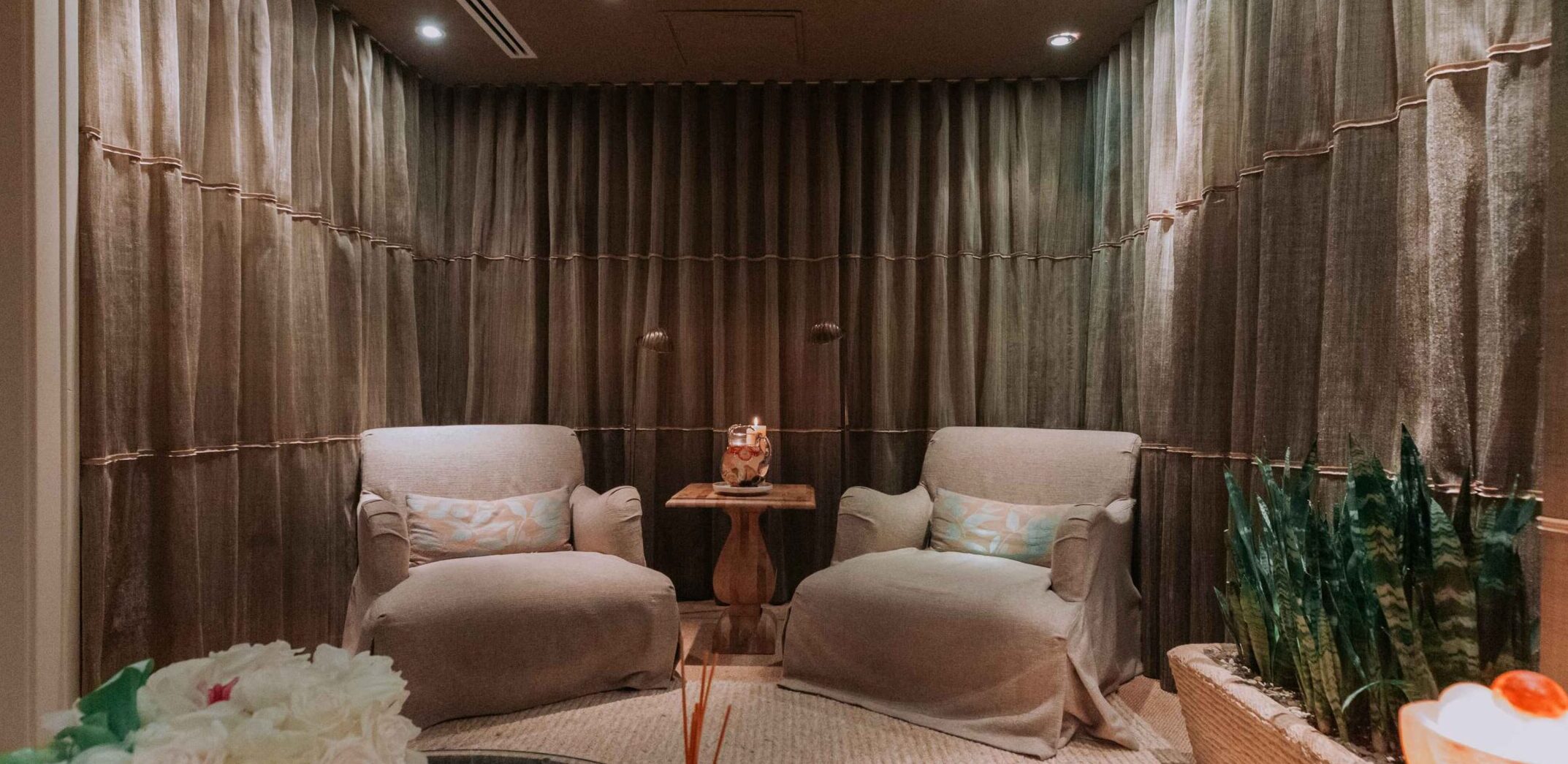 A cozy spa room with two armchairs, soft lighting, and calming decor.