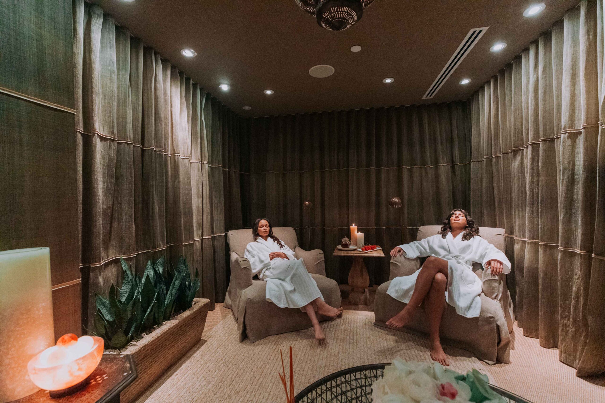 2 women wearing robes, reclining in chairs in the spa seating area