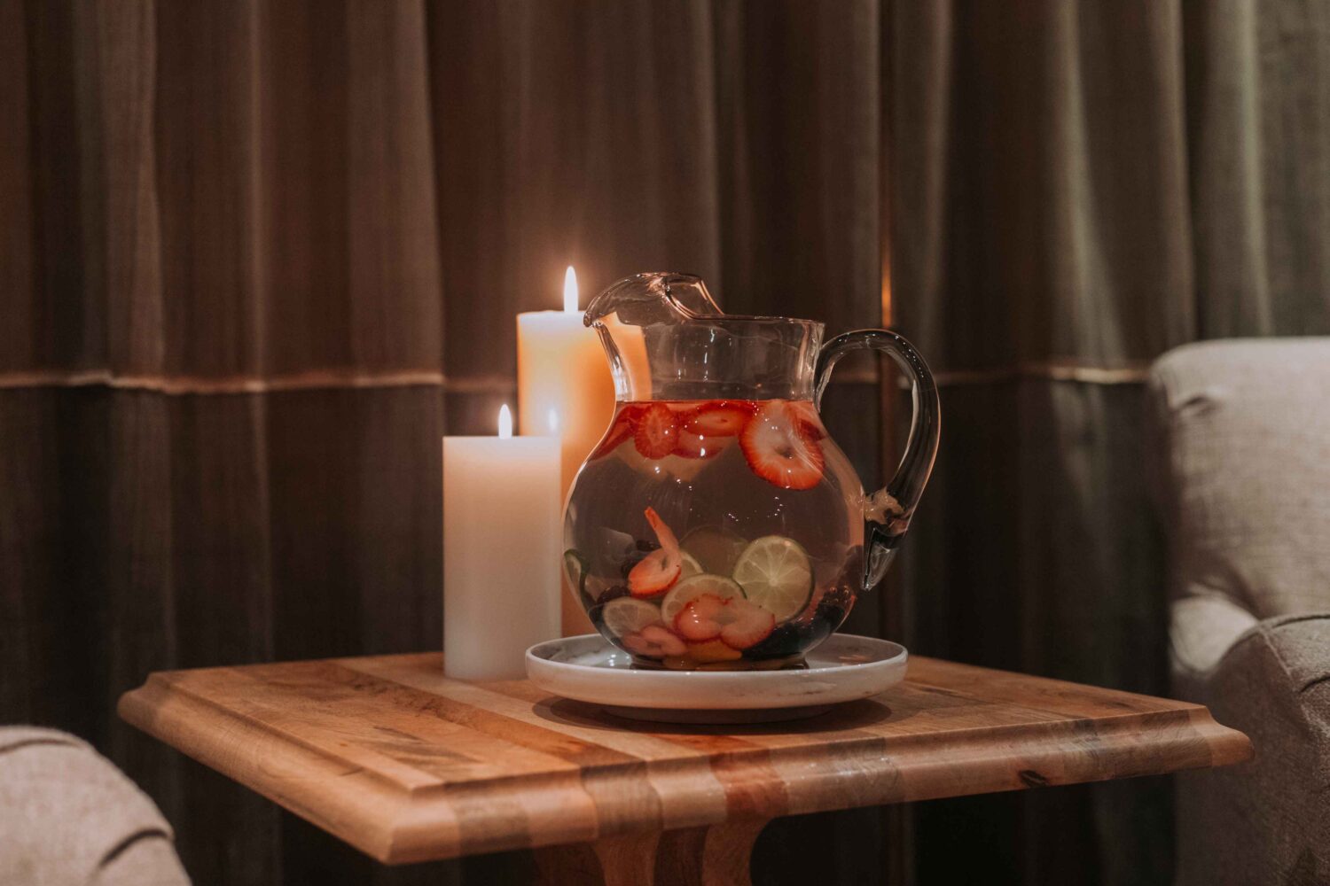 pitcher of fruit infused water on a table alongside candles