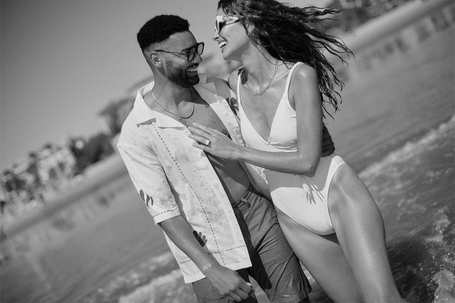 b&w image: man and a woman laughing and facing each other, walking in the ocean